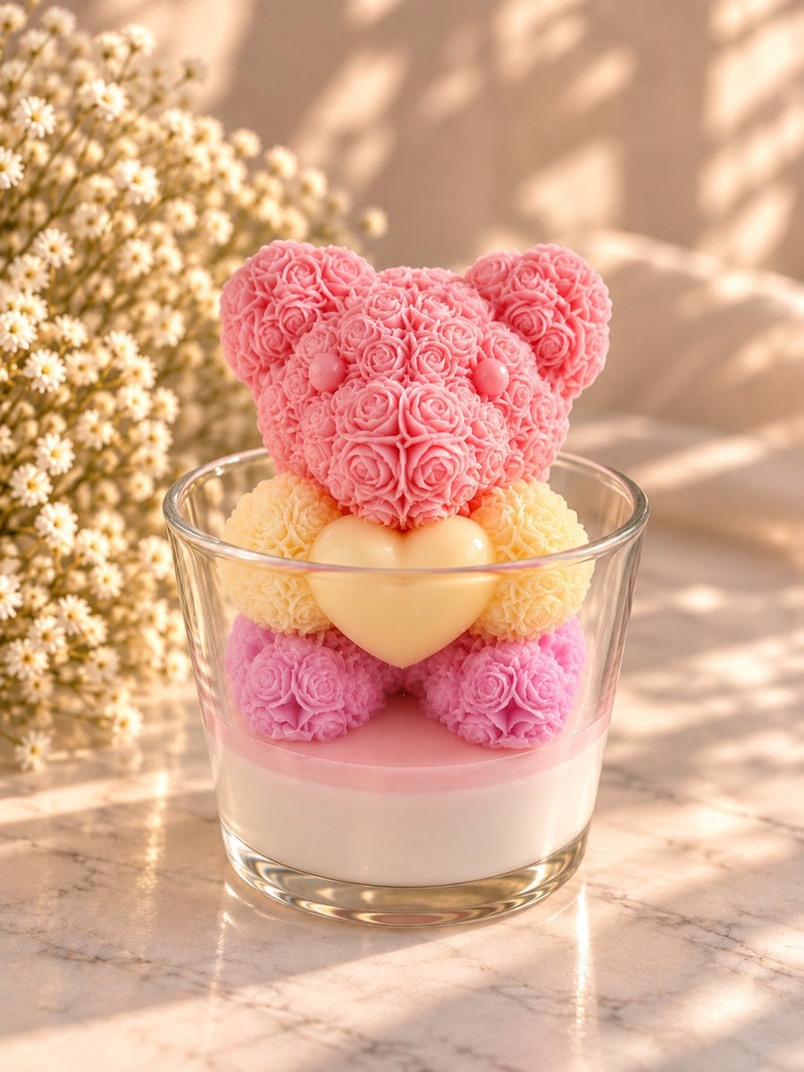 Bougie ourson en roses rose et jaune posé sur une bougie coulée en verre